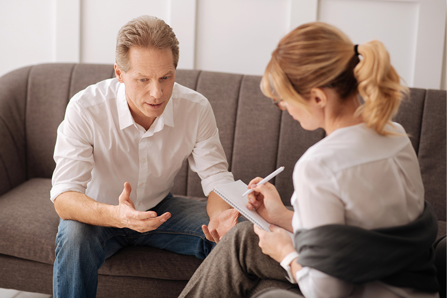 Man in a therapy session with a counselor, discussing a treatment approach for anxiety through personalized mental health care.