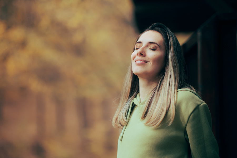 Serene woman practicing mindfulness breathing outdoors for personality disorder treatment in a natural autumn setting Residents enjoy sober living services in San Diego, an addiction recovery community focused on personal growth and a sober lifestyle
