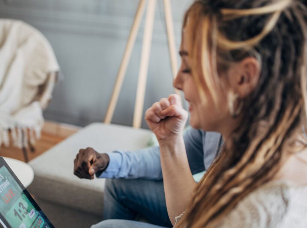 A woman pumps her fists as she sits with friends during online betting