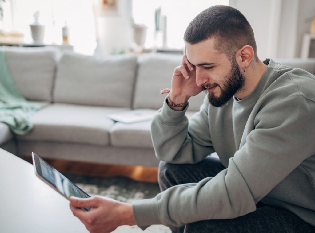 A man is sitting at home and using his tablet for online gambling